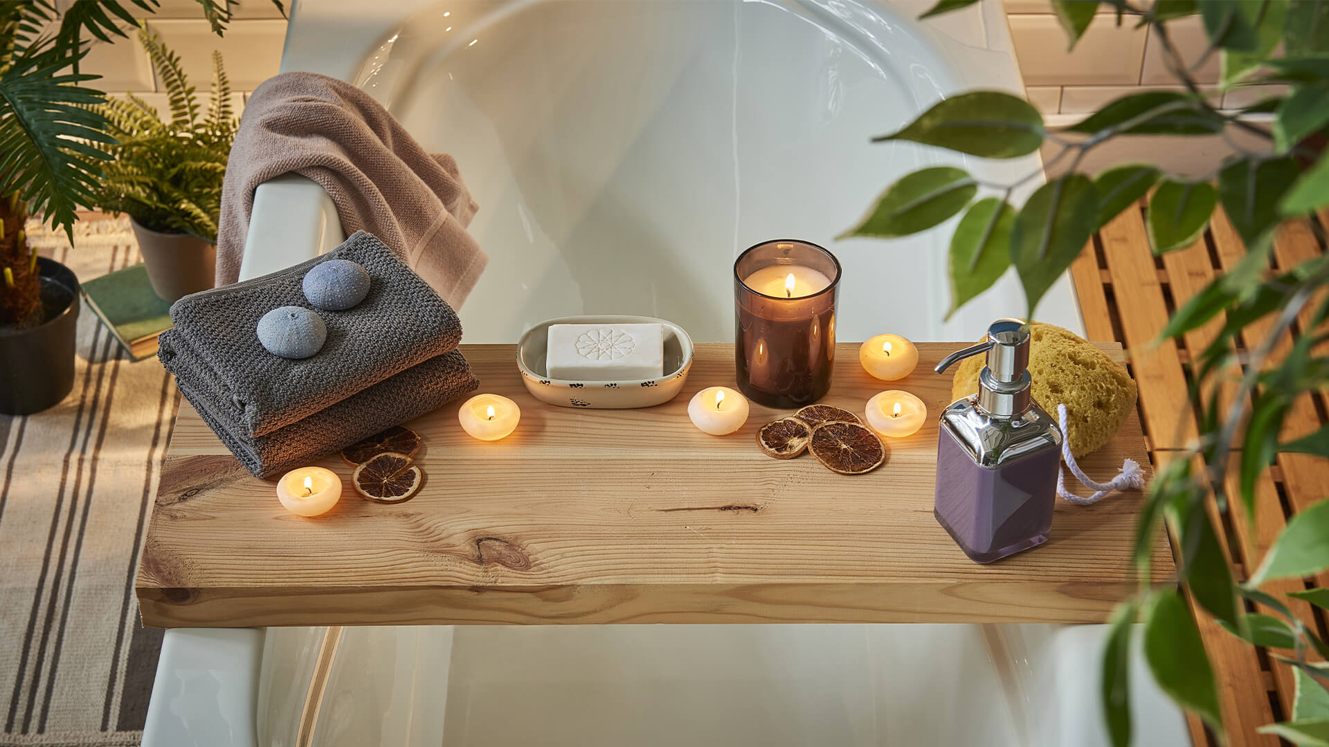 Bathtub with tray, candles, towels, plants, and bar soap
