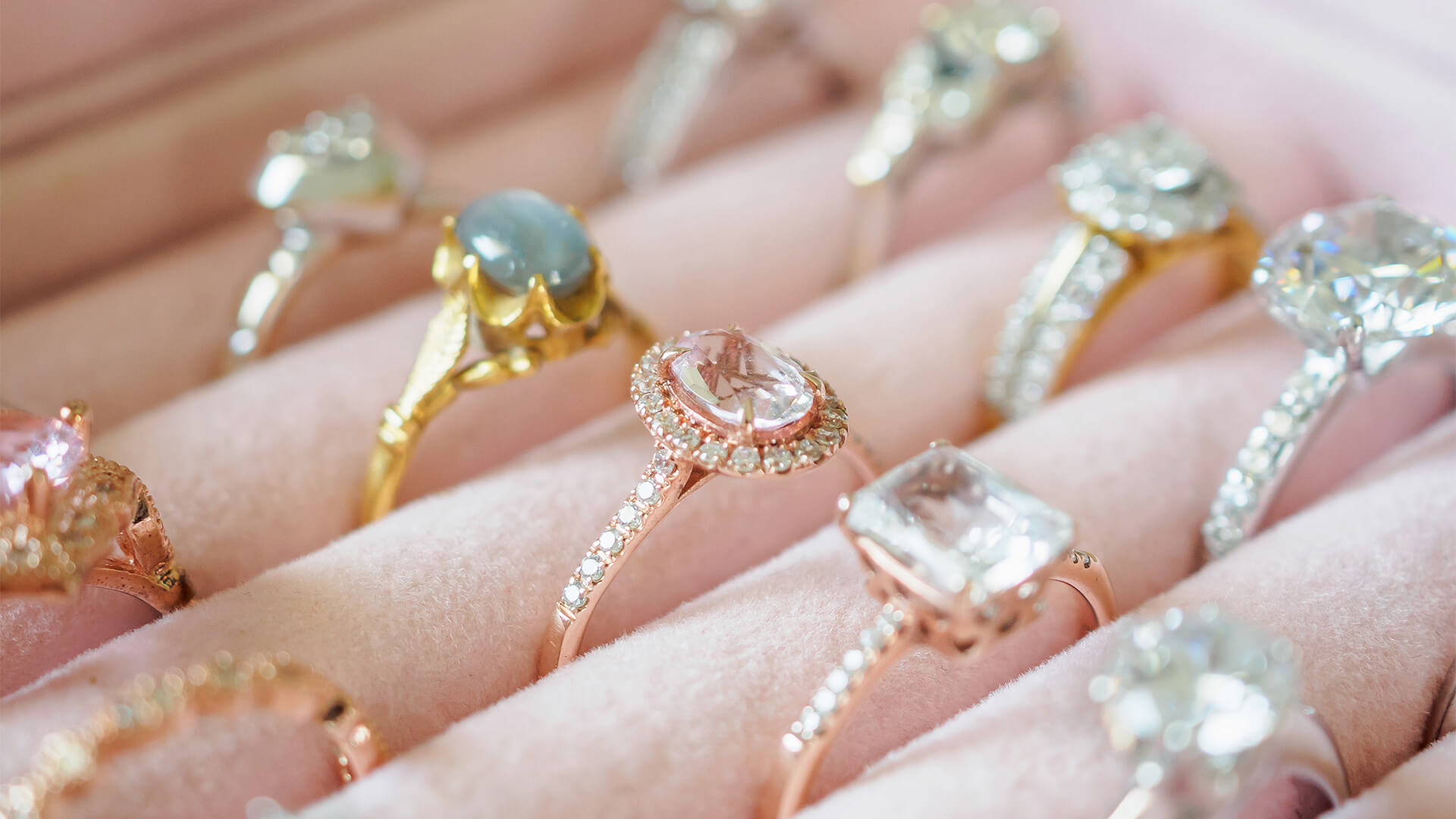 A collection of gold, silver, and rose gold rings in a pink jewellery box