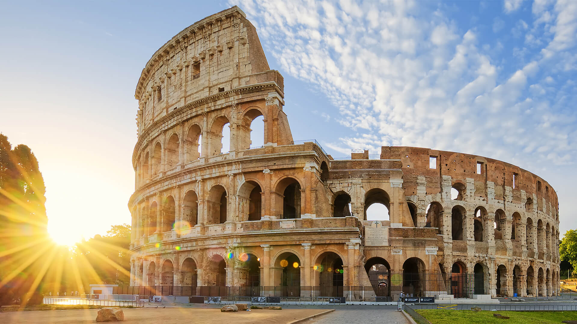 The Colosseum in Rome with the sun shining behind it
