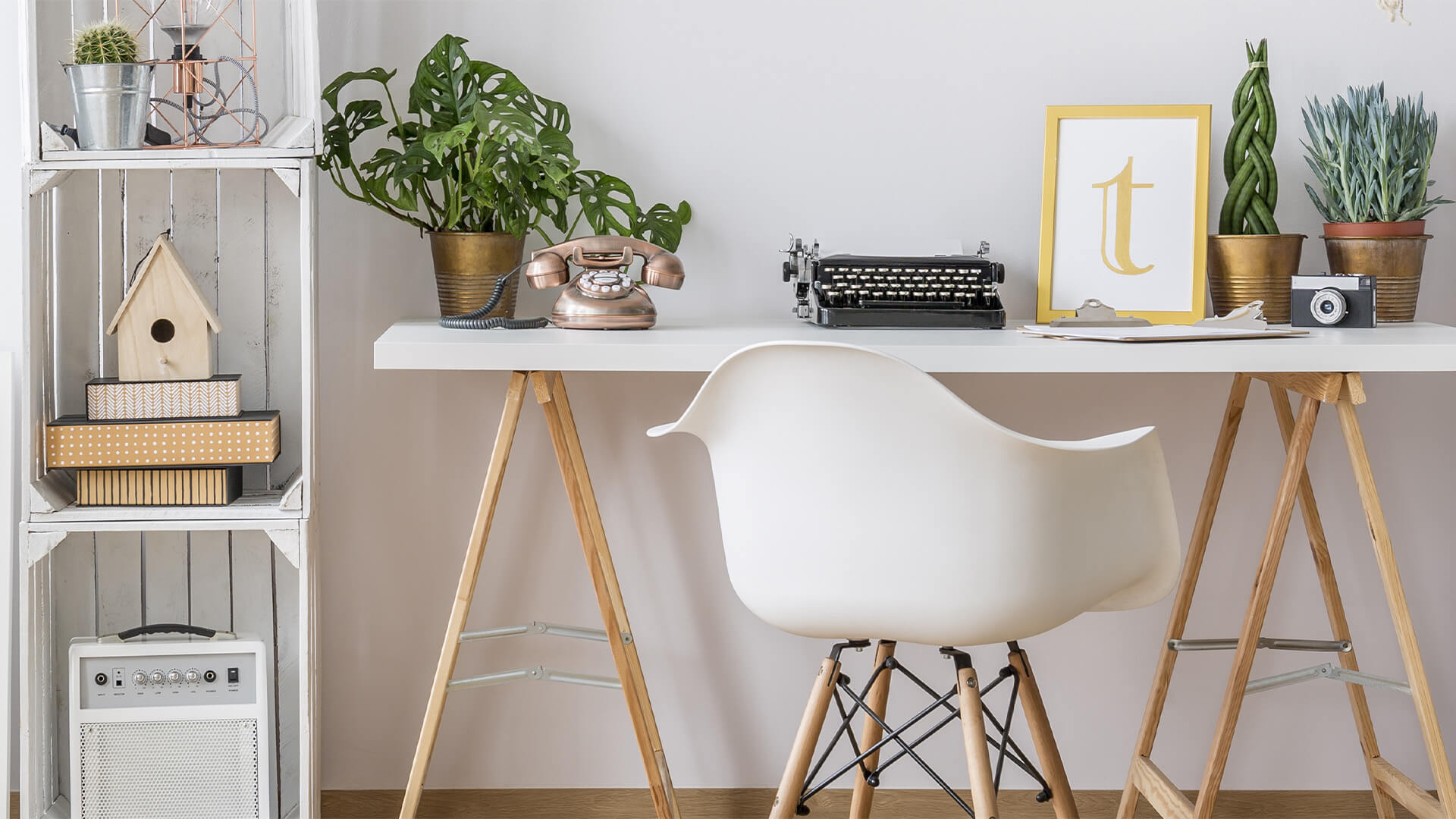 Stylish home office with a white shabby chic desk, typewriter, plants, wooden bookcase