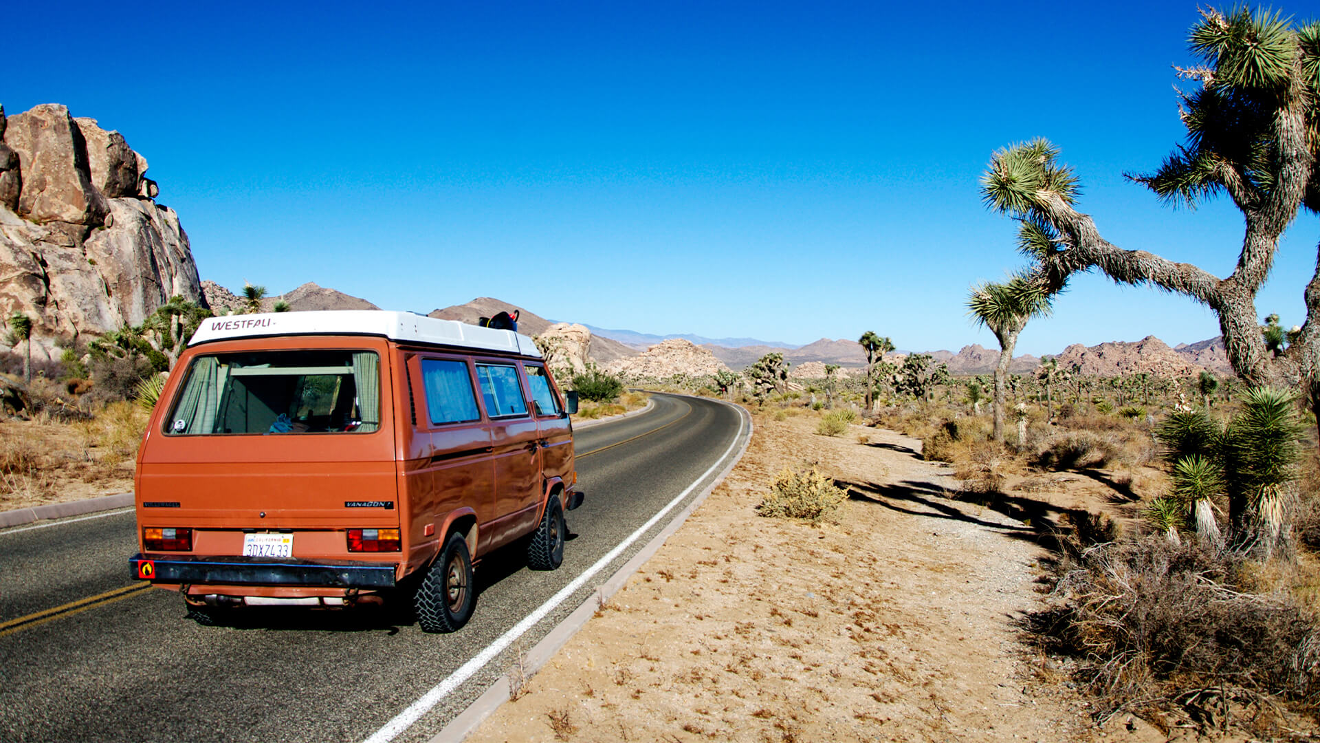 Orange vintage camper van on a road trip through the desert
