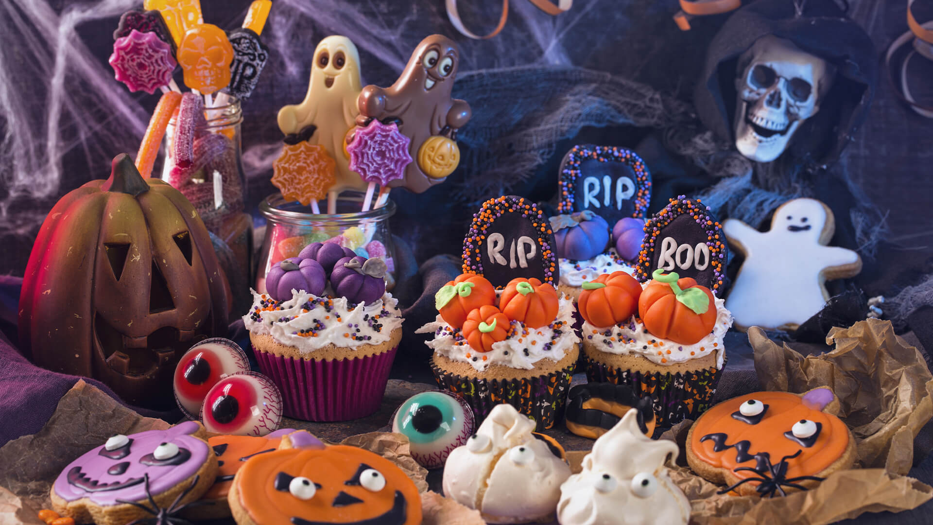 Halloween decorated cakes and biscuits with a spooky purple background