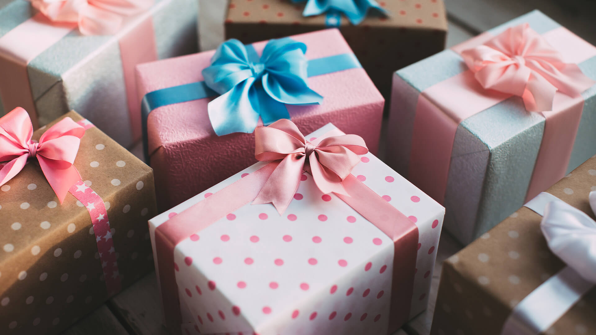 Neatly wrapped boxes with pink and blue gift wrap and ribbons