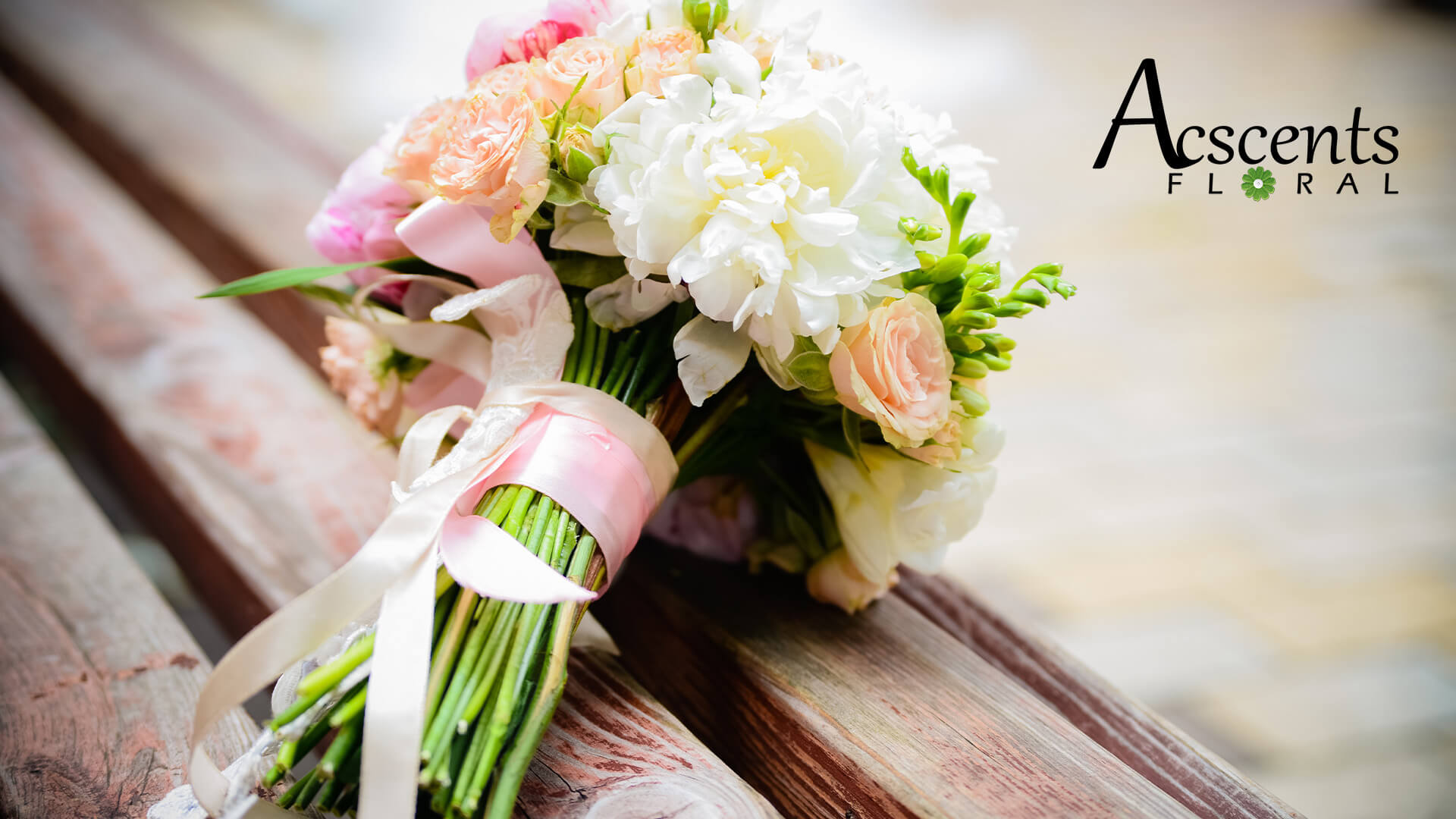 White, orange, and pink wedding bouquet with the Ascents Floal logo in the top right corner