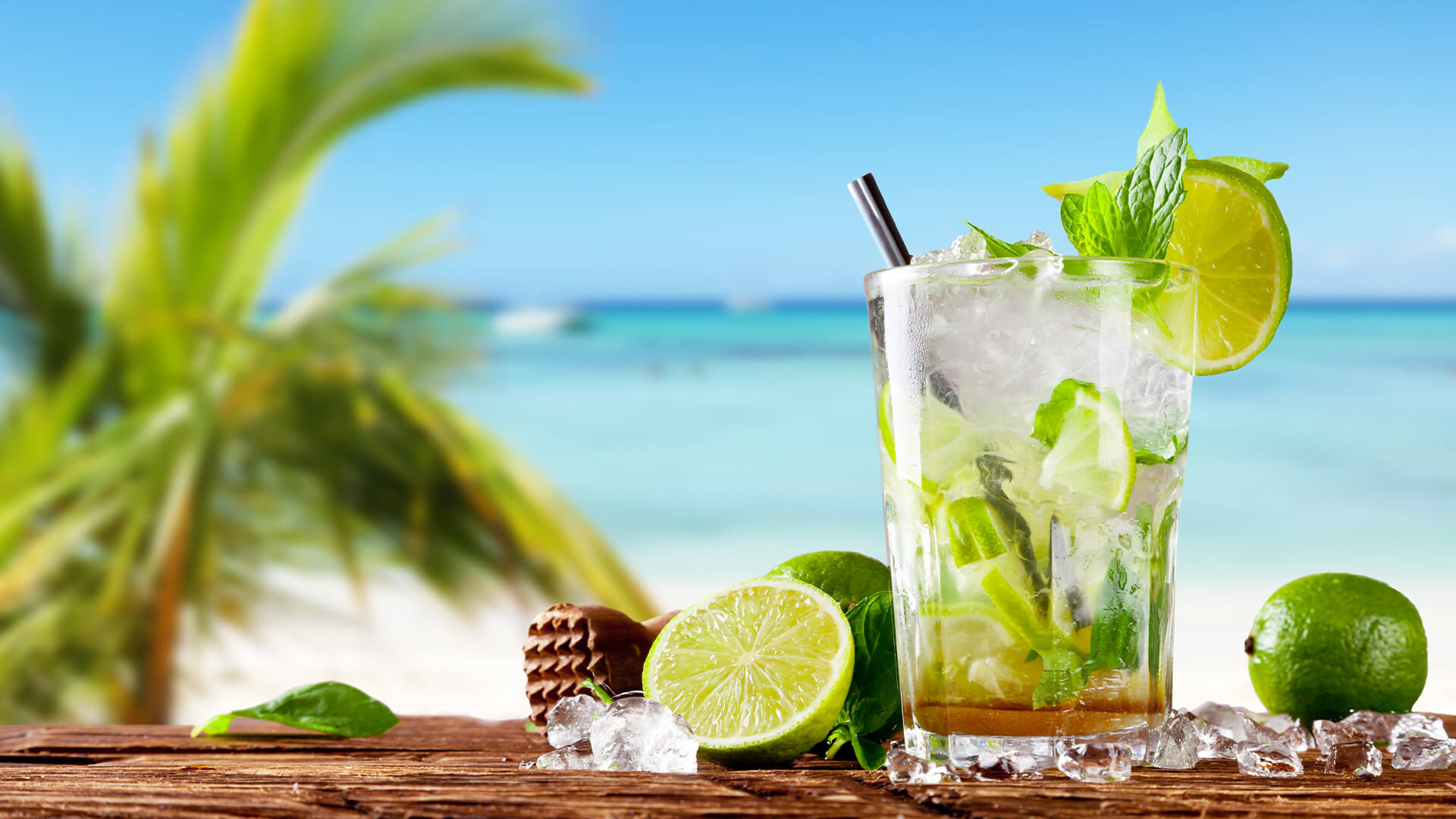 Mojito in the foreground, with palm trees and a beach on a sunny day in the background