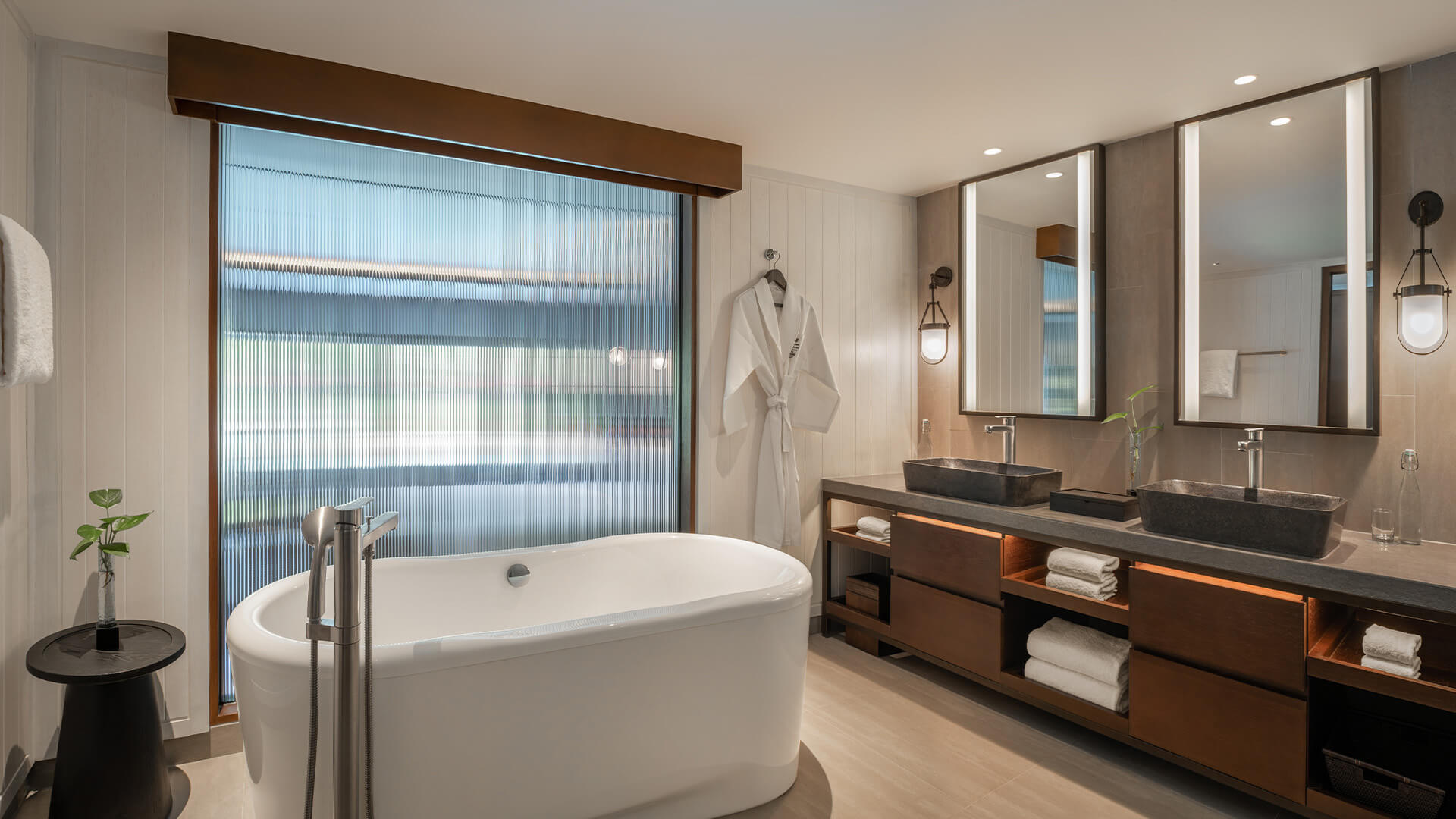 A luxury bathroom of a studio room at The Laguna Resort showing a large bathtub, robe, large mirror and sink