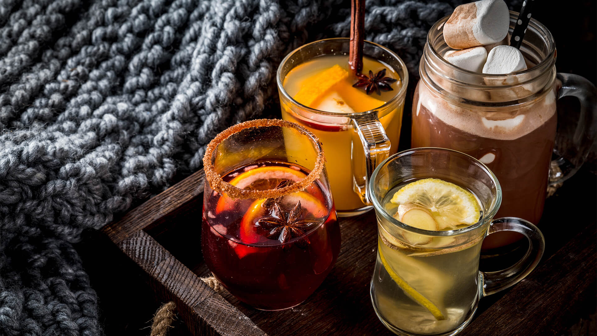 Selection of various autumn traditional drinks: hot chocolate with marshmallow, tea with lemon and ginger, white pumpkin spicy sangria, mulled wine. On wooden rustic table,