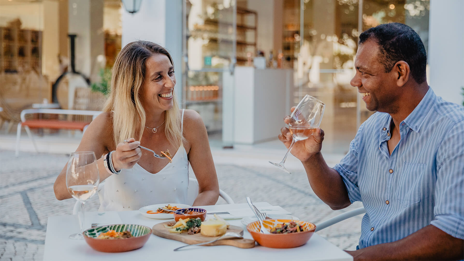 man and woman sitting at table eating food and drinking wine