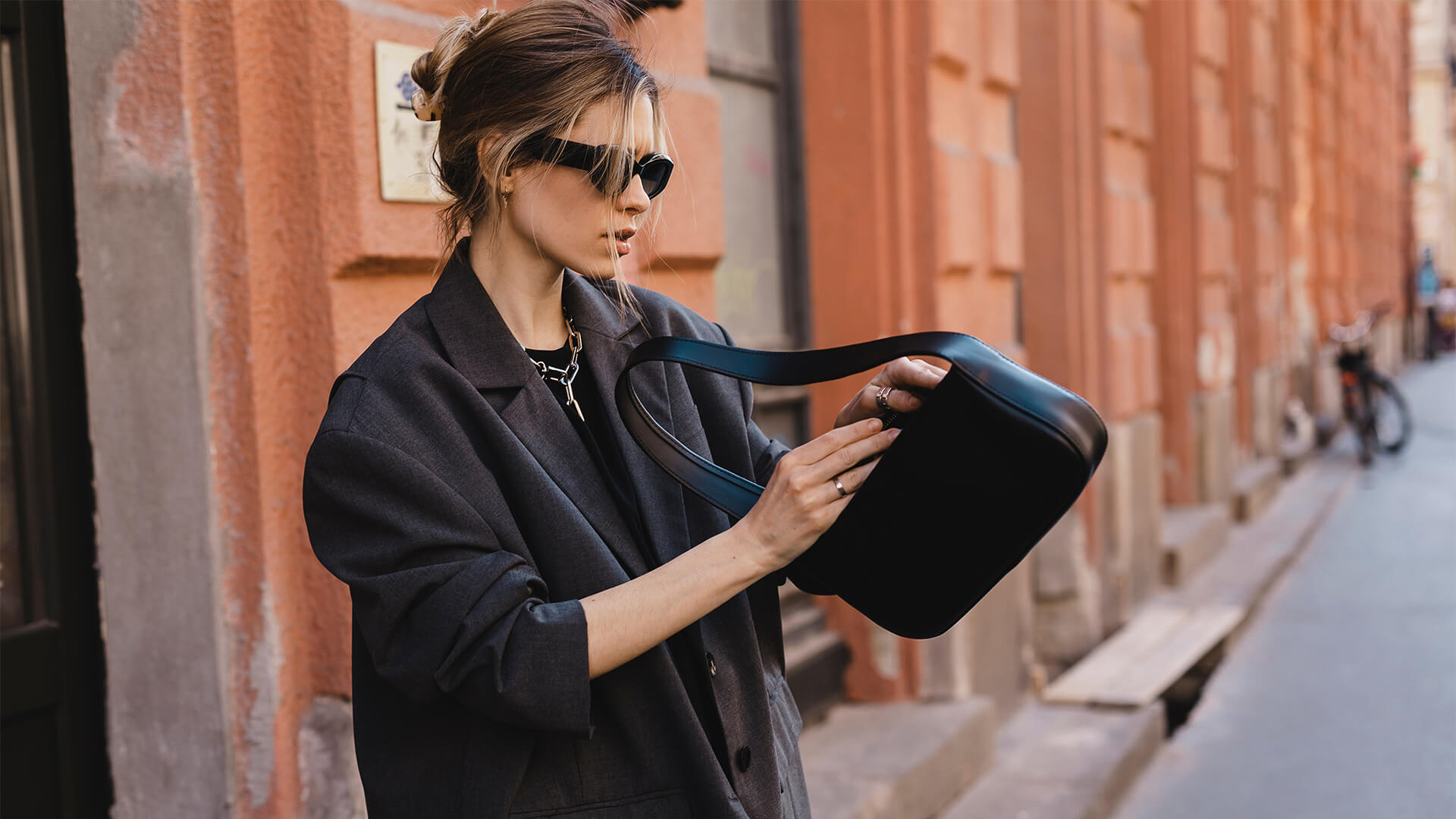 Elegant young woman looking in her black leather bag