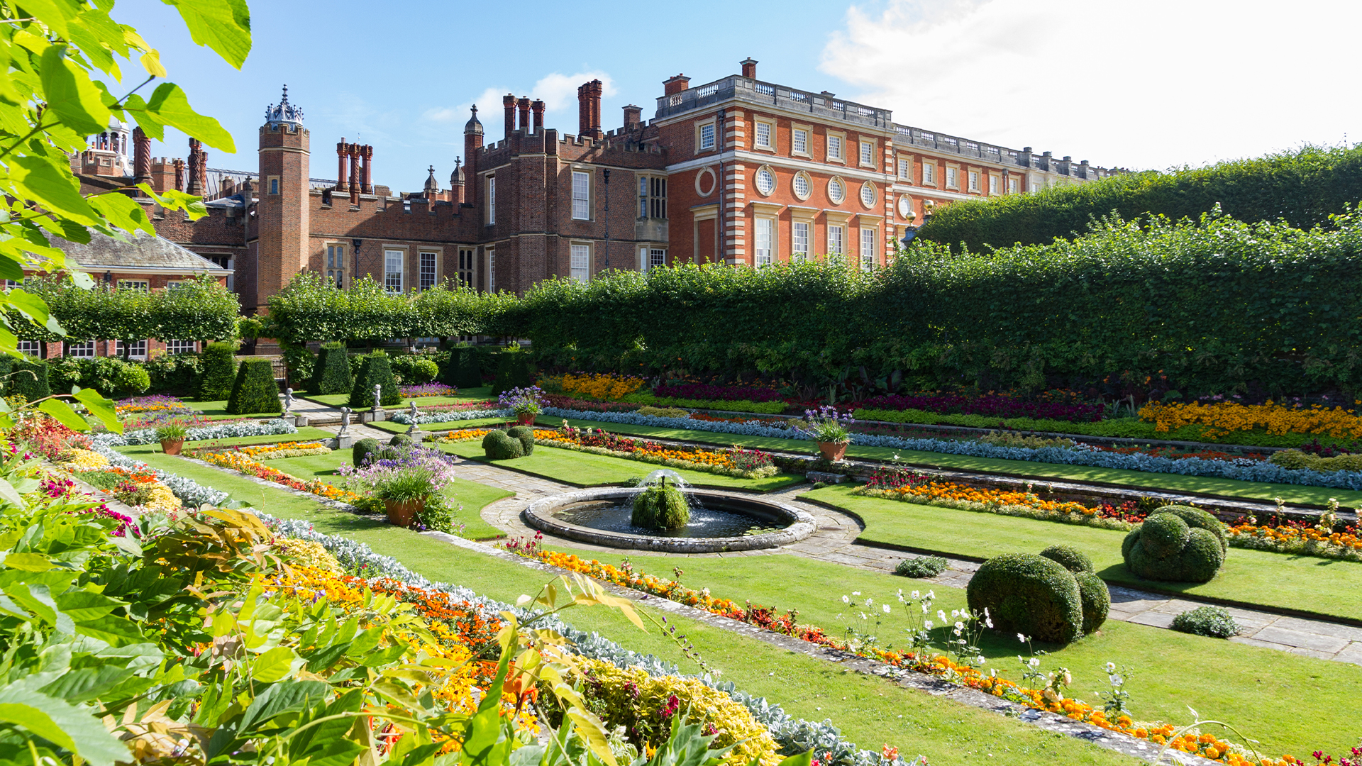 Georgian and Tudor Facades of Hampton Court Palace with the foreground showing the colorful sunken gardens